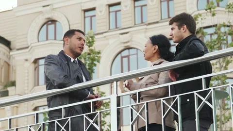 Engaging conversation among three professionals on a city street Stock Footage 311981149