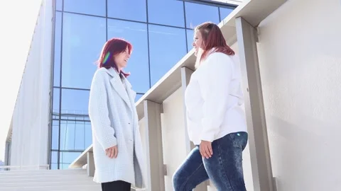 Engaging conversation between friends at a modern building under bright sunlight Stock-Footage 295273894