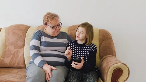 Engaging conversation between grandmother and granddaughter on a cozy sofa Stock Footage 305160401