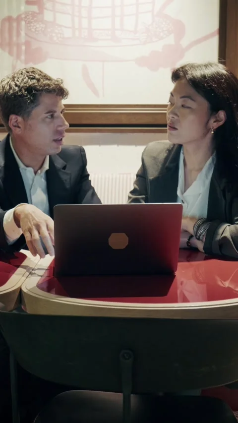 Engaging conversation between two young professionals at a cafe with a laptop 库存影片 305982630