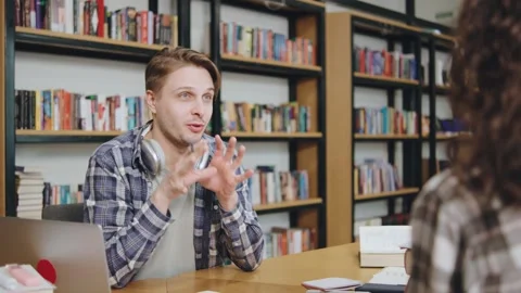 Engaging conversation between a young man and woman in a library setting during Stock Footage 308667959