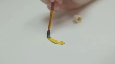 Engaging in the Creative Painting Process using Yellow Paint and a Brush for Stock Footage 307449477