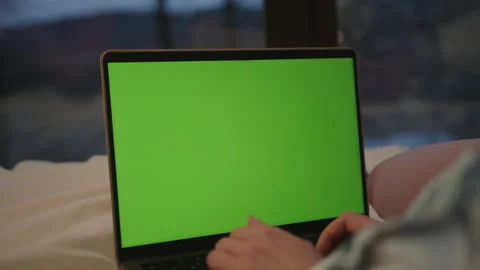 Engaging in creative work on a laptop with a green screen in a indoor setting Stock Footage 309276172