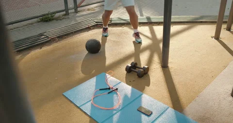 Engaging in a Dynamic Outdoor Workout using Weights along with a Jump Rope for Stock Footage 317756376