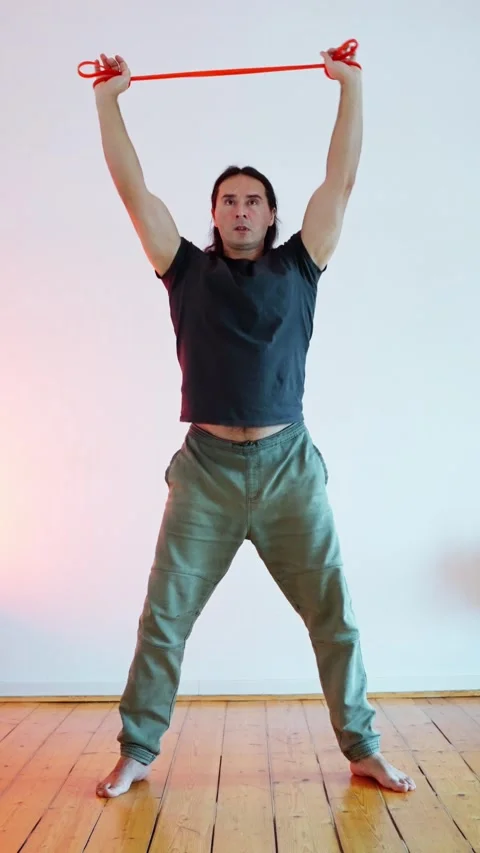 Engaging in Dynamic Stretching using a Resistance Band for Enhanced Fitness and Stock Footage 304801633
