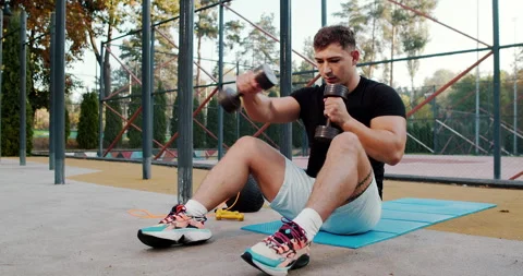 Engaging in a Focused Strength Training Session with Dumbbells in an Outdoor Video stock 317979173