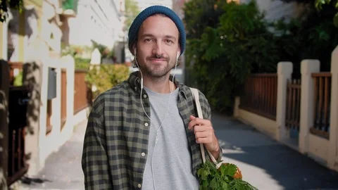 Engaging Hispanic guy standing with Eco grocery bag and pleasant smiling to the Stock Footage 111071489