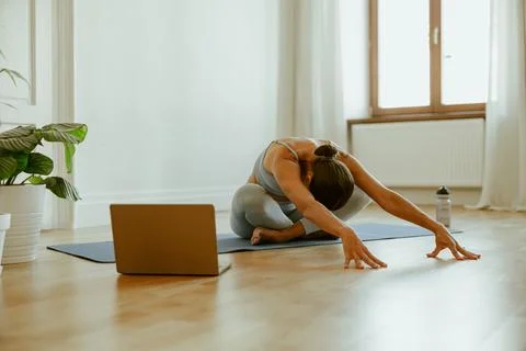 Engaging in Home Yoga Practice using a Laptop while Enjoying the Natural Light Stock Photos