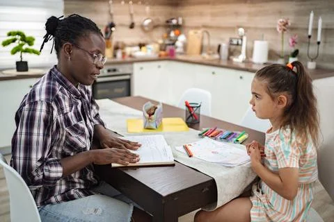 Engaging learning moments between a girl and her mentor at home Stock Photos