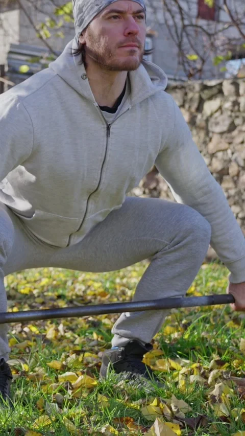 Engaging in Outdoor Strength Training with a Barbell during the Beautiful Autumn Stock Footage 312476271