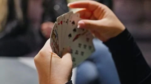 An engaging scene of a card game featuring players intensely focused on their Stock Footage 317235574