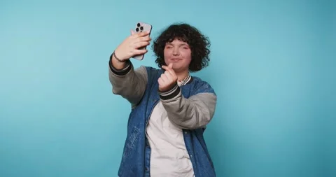 Engaging selfie session with cheerful individual against a vibrant blue bac.. Stock Footage 313951549