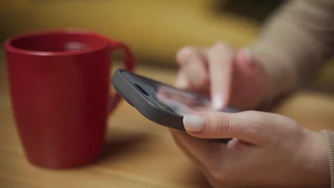 Engaging with a smartphone while enjoying coffee in a cozy setting during the Stock-Footage 303768560
