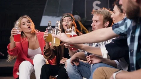 Engaging stylish young mates sitting on the chairs and giving high five with Stock Footage 116667311