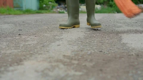 Engaging in the task of cleaning the ground while wearing sturdy rubber boots Stock Footage 308396081