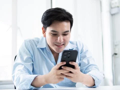 Engaging with technology young man using smartphone indoors modern workspace Stock Photos