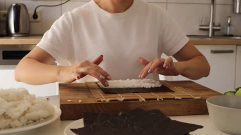 In this engaging tutorial, a woman demonstrates the art of sushi-making at home 動画素材 316681794