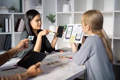 Engaging UX UI design discussion with mobile app prototypes and team feedback. Stock Photos
