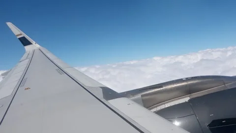An engine and wing visible through a passenger window above a sea of clouds. Stock Footage 345353942