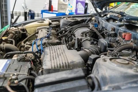 Engine components and wiring in a vehicle being serviced at a garage Fotos Stock