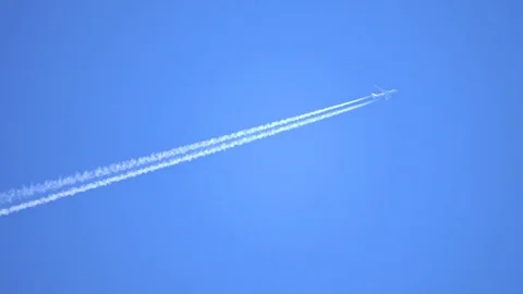 Engine exhaust contrails forming behind flying commercial airplane Stock Footage