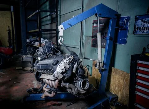 Engine instalation on blue crane hook on car repair service Stock Photos