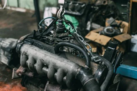 Engine instalation on crane hook on car repair service Foto stock