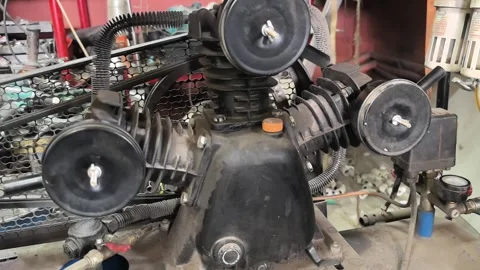 Engine maintenance work in a garage setting focusing on a small air compressor u Stock Footage 309331977