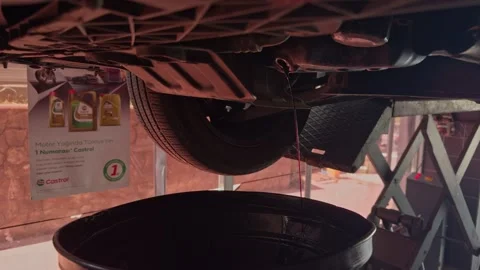 Engine Oil Draining from Lifted Car into Drain Pan Video stock 344015581