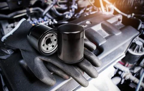Engine oil filter and auto mechanic gloves on engine cover Fotos de archivo