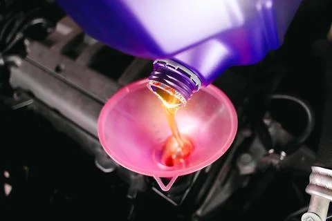 Engine oil poured into a funnel in the engine oil filler of the car engine Stock Photos