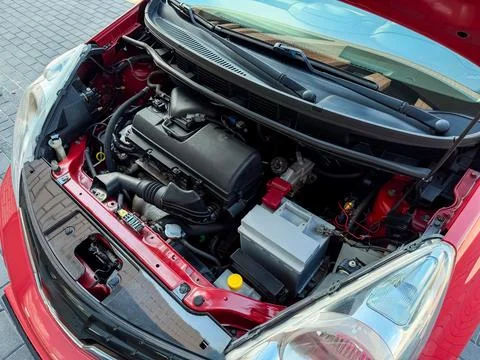 Engine view of a red car with open hood showing various parts and component.. Stock Photos