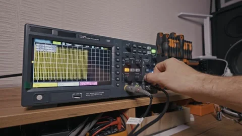 Engineer Adjusting Oscilloscope Waveform on Digital Display in Lab Stock Footage 327554612