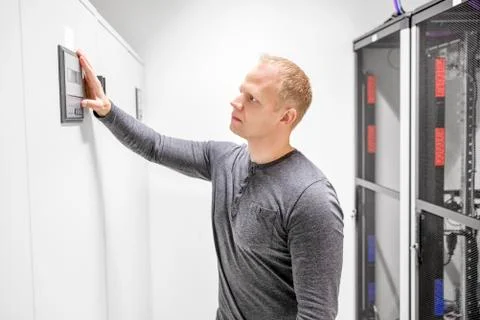 Engineer adjusts air conditioner in datacenter Stock Photos