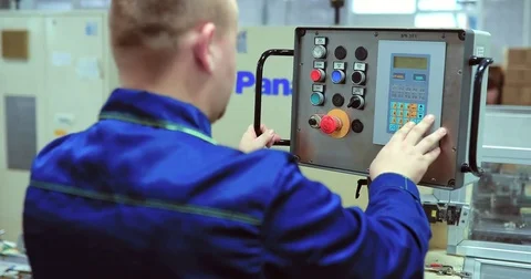 Engineer adjusts the conveyor / presses the buttons on the control panel in the Stock Footage 82954671