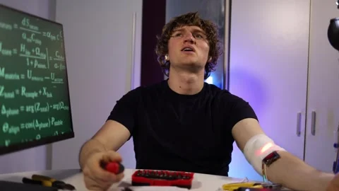Engineer adjusts glowing arm implant while coding neural systems in home lab Video stock 324443208