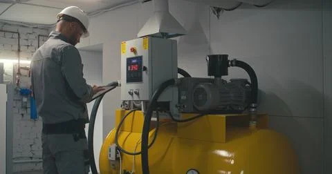 Engineer adjusts vacuum pump station using tablet computer 스톡 사진
