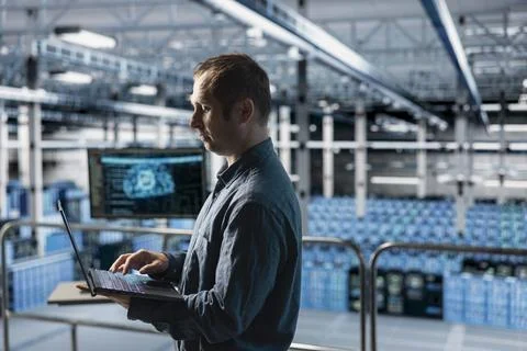 Engineer in AI data center managing software updates using laptop 스톡 사진