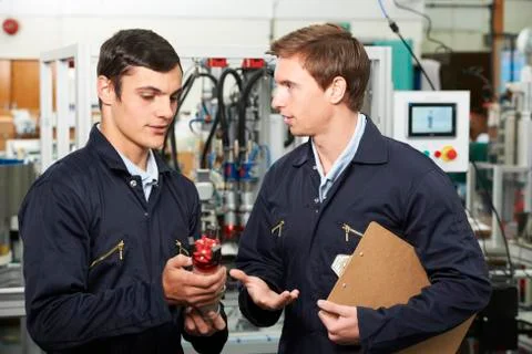 Engineer And Apprentice Discussing Component In Factory Foto stock