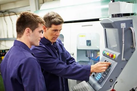 Engineer and apprentice using automated milling machine Stock Photos