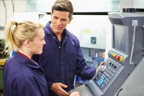 Engineer and apprentice using automated milling machine 스톡 사진