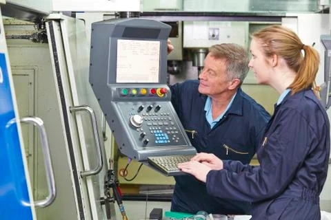 Engineer And Apprentice Using Computerized Cutting Machine Stock Photos