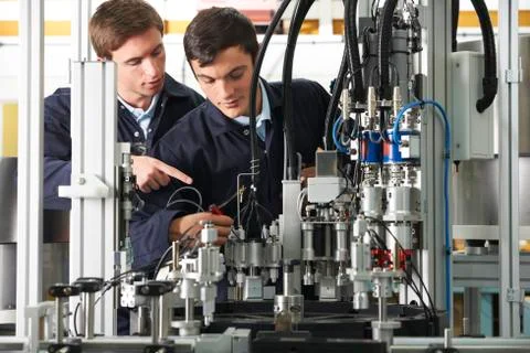 Engineer And Apprentice Working On Equipment In Factory Stock Photos