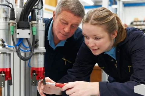 Engineer And Apprentice Working On Machine In Factory Stock Photos