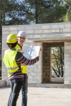 Engineer and architect looking at the plan of a house under construction Stock Photos