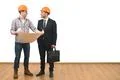 The engineer and a businessman stand with a paper on the white wall backgroun Photo