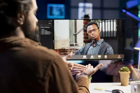 Engineer and colleague in remote videoconference writing code on PC Stock Photos