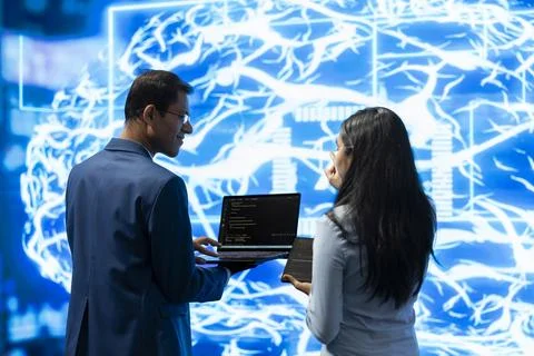 Engineer and coworker using laptop and tablet to look at AI digital brain Stock Photos