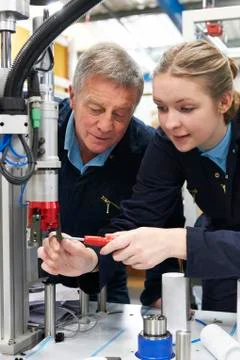 Engineer And Female Apprentice Working On Machinery In Factory Foto stock