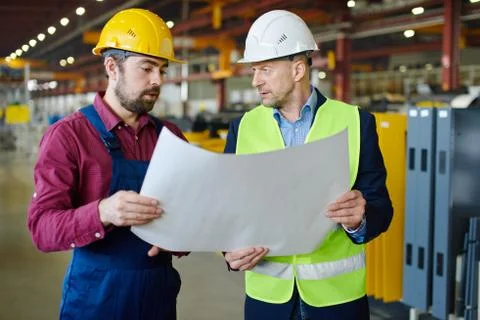 Engineer and foreman are discussing the new project at the factory Stock Photos